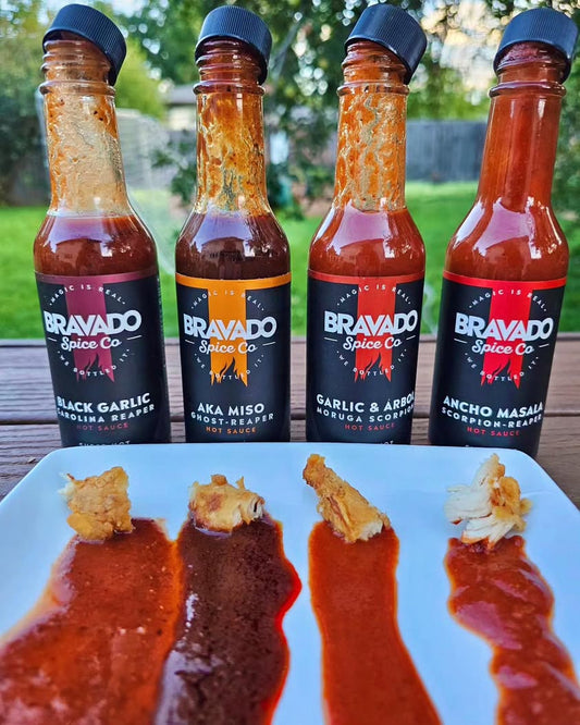 Four hot sauces from Bravado Spice Co. highlighting distinct flavor profiles and heat levels with tasting samples on a plate.