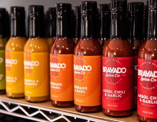 A lineup of Bravado Spice Pineapple & Habanero, Serrano & Basil, and Arbol Chili & Garlic hot sauces.