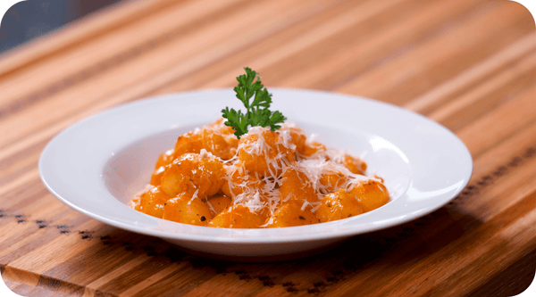 gnocchi in a white bowl with basil garnish