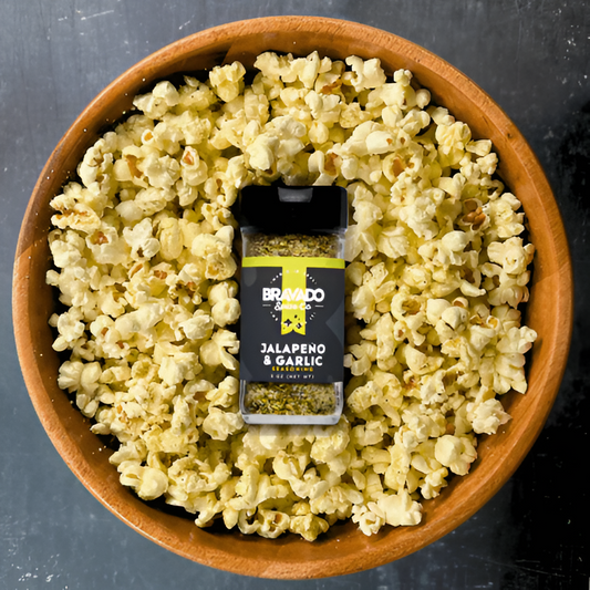 A wooden bowl of popcorn wth Bravado Spice Co. Jalapeno & Garlic seasoning.